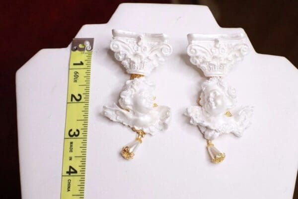 A pair of white porcelain wall hangers with gold trim.