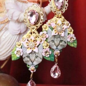 A pair of earrings with cats and flowers on them.