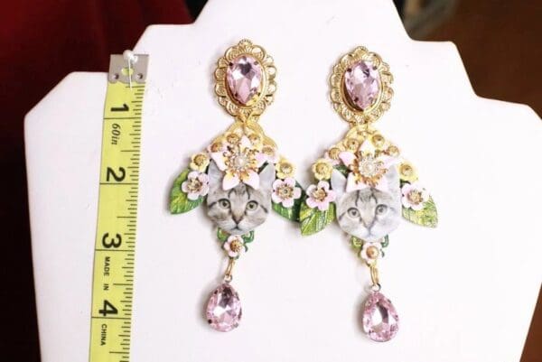 A pair of earrings with pink stones and gold leaves.