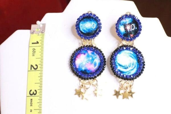 A pair of earrings with the image of a galaxy and stars.