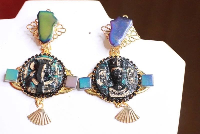 A pair of earrings with faces and a fan