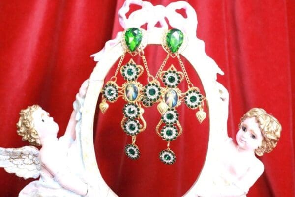 A pair of earrings hanging from chains on top of a mirror.