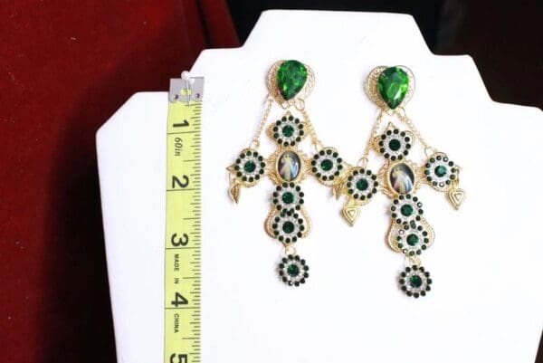 A pair of earrings with green stones hanging from them.