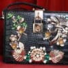 A black purse with flowers and leaves on it.