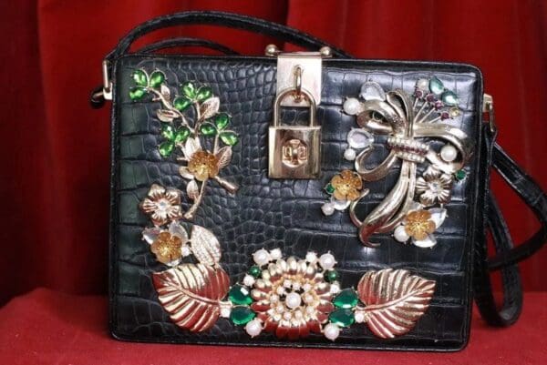 A black purse with flowers and leaves on it.