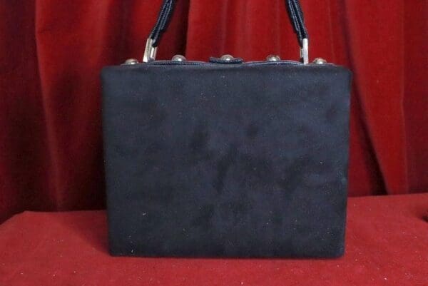 A black purse sitting on top of a red table.