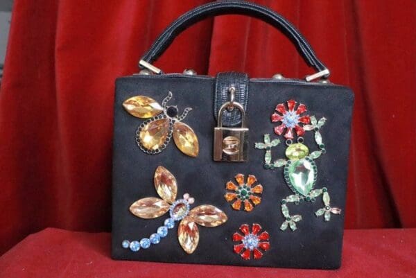 A black purse with various designs on it.