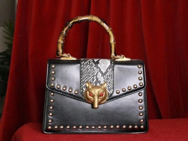 A black purse with gold accents and a metal handle.