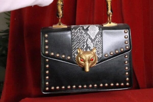 A black purse with gold accents and a red background