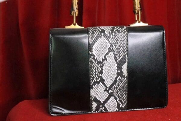 A black purse with a snake print on the front.