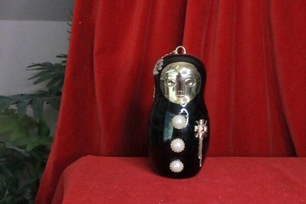 A black doll with white balls and a cross on it.