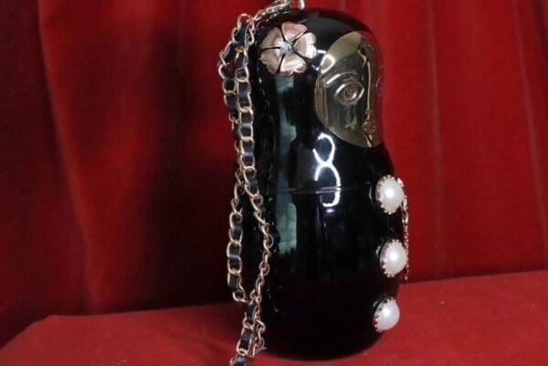 A black russian doll with pearls and flowers on it.