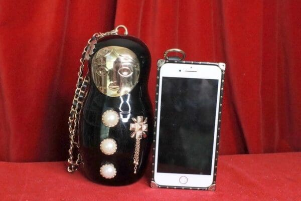 A cell phone is next to a russian doll purse.