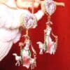 A pair of earrings with a woman and sheep hanging from chains.