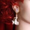 A woman with red hair wearing earrings and a white dress.