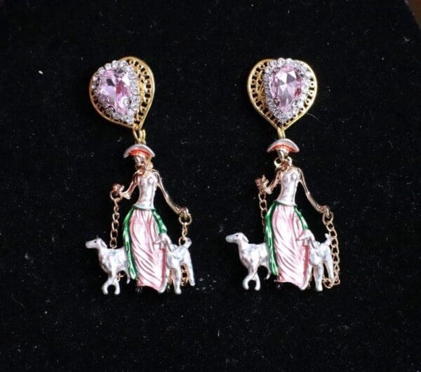 A pair of earrings with a woman and sheep.