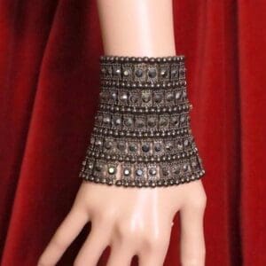 A hand wearing a bracelet with multiple rows of stones.
