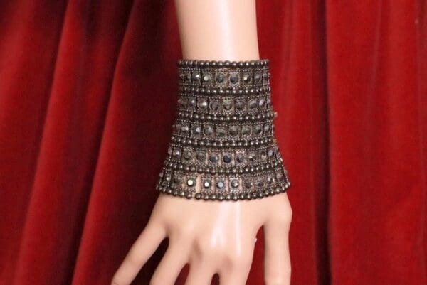 A hand wearing a bracelet with multiple rows of stones.