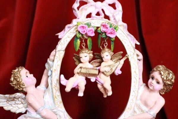 A pair of angels hanging from the side of a picture frame.