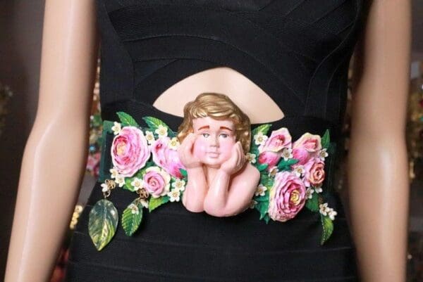 A woman wearing a black dress with pink flowers around her waist.