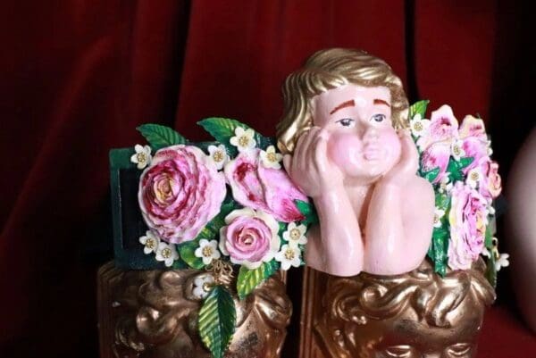 A statue of a cherub with flowers on it.