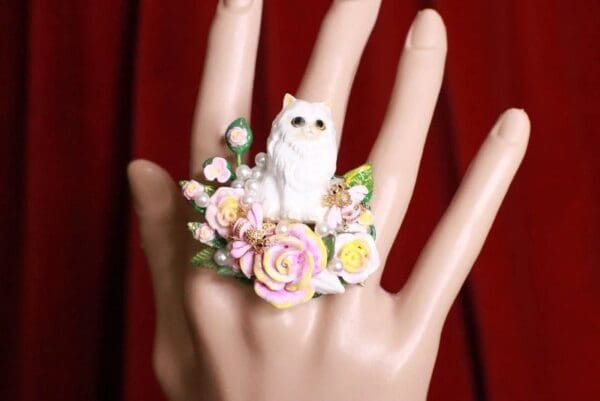 A hand with a cat ring on it