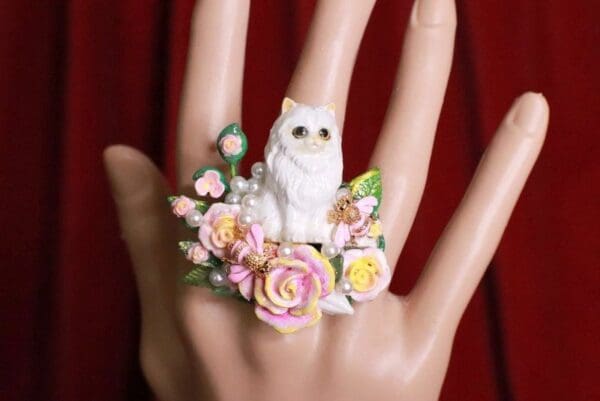 A hand with a ring on it and flowers around the finger.