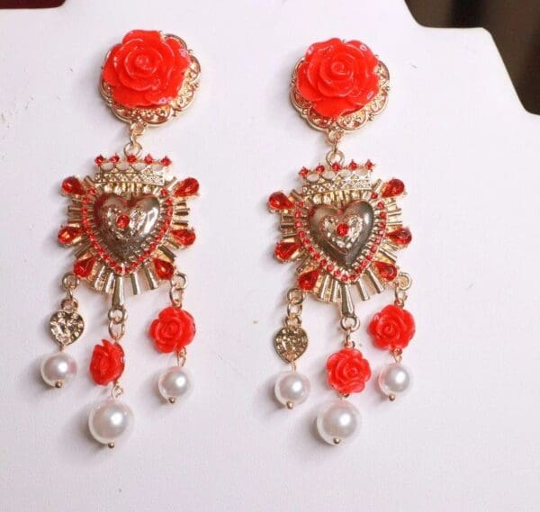 A pair of red earrings with pearls and flowers.