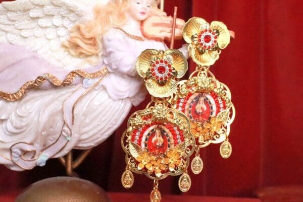 A pair of earrings with red and gold design.