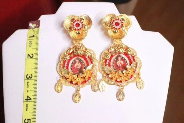 A pair of gold earrings with red and yellow designs.