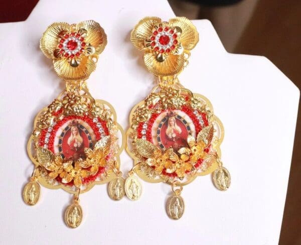 A pair of earrings with red and gold design.