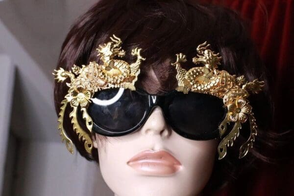 A woman wearing sunglasses with gold dragon decorations on them.
