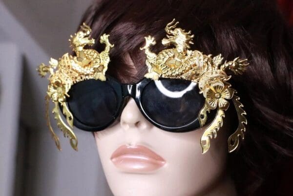 A mannequin wearing gold sunglasses with dragon heads on them.