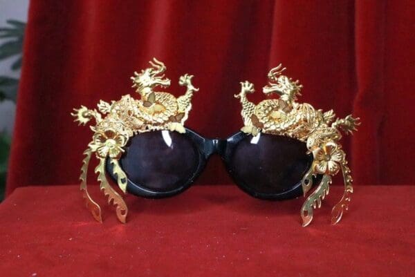 A pair of sunglasses with gold dragon heads on them.