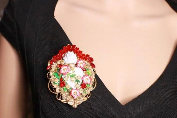 A woman wearing a brooch with red and green beads.