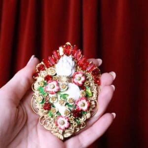 A person holding a small ornate ornament in their hand.