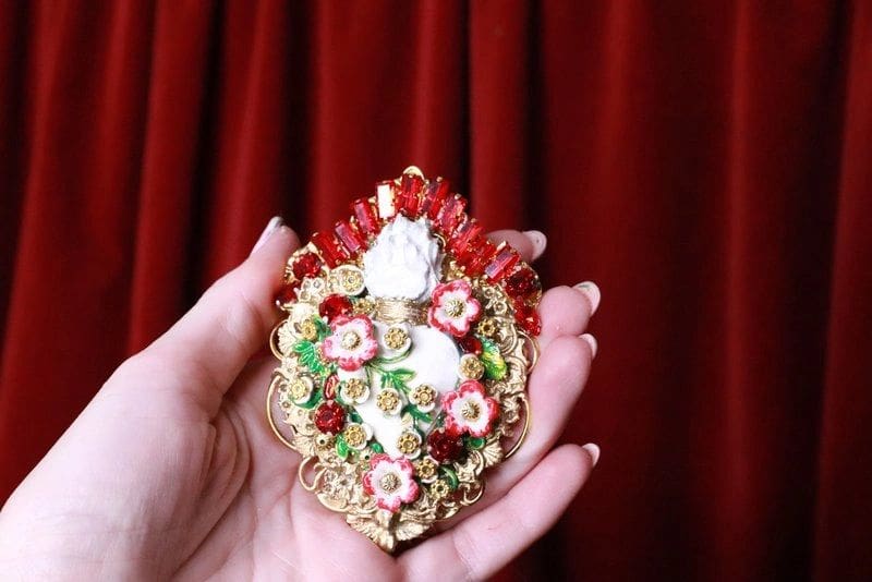 A person holding a small ornate ornament in their hand.
