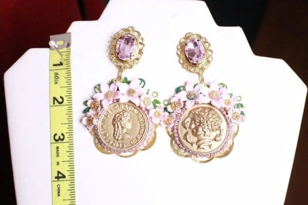 A pair of earrings with gold coins and flowers.