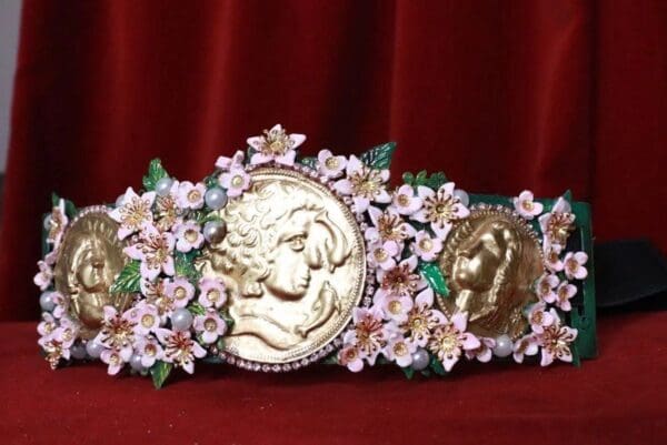 A gold coin and pink flowers on a red velvet background.