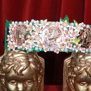 A pair of gold statues with flowers on top