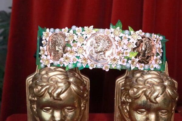 A pair of gold statues with flowers on top