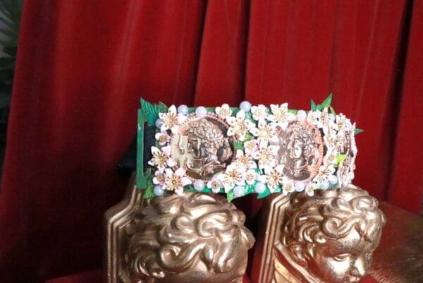 A pair of gold statues with flowers on top.