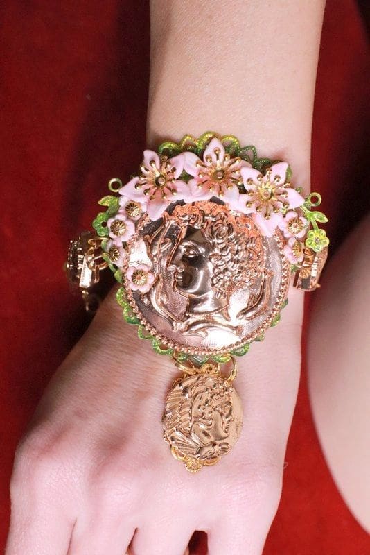 A woman wearing a bracelet with flowers and a coin.