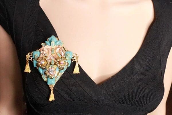 A woman wearing a black top and a blue brooch.
