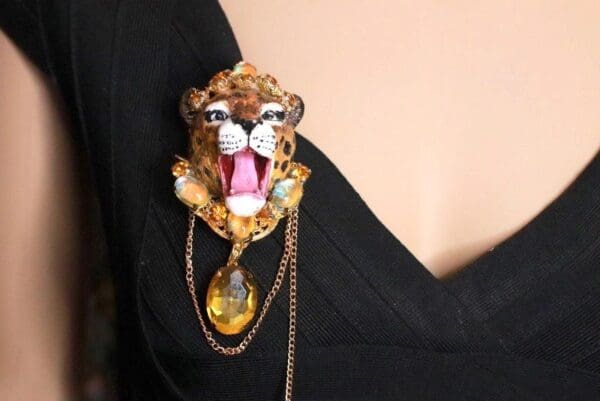 A woman wearing a black dress with a leopard brooch.