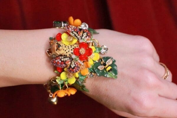 A woman wearing a bracelet with flowers and leaves.