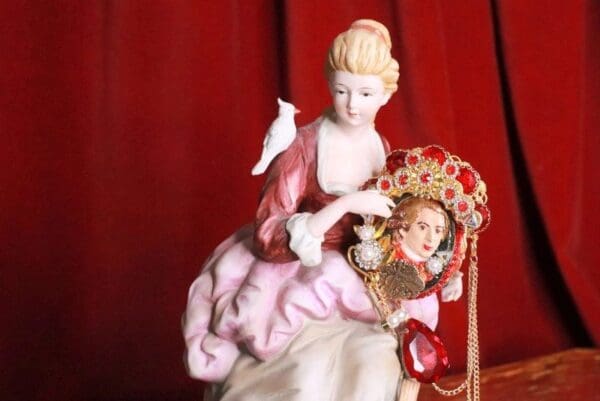 A porcelain figurine of a woman and a doll.