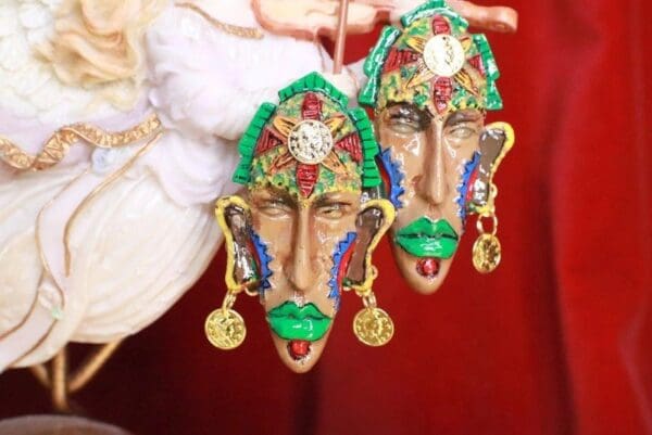 Two green and gold masks hanging from a red wall.