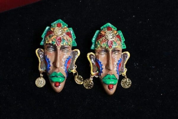 A pair of colorful face earrings with gold coins.