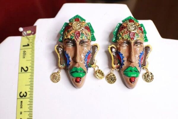 A pair of earrings with faces and gold coins.